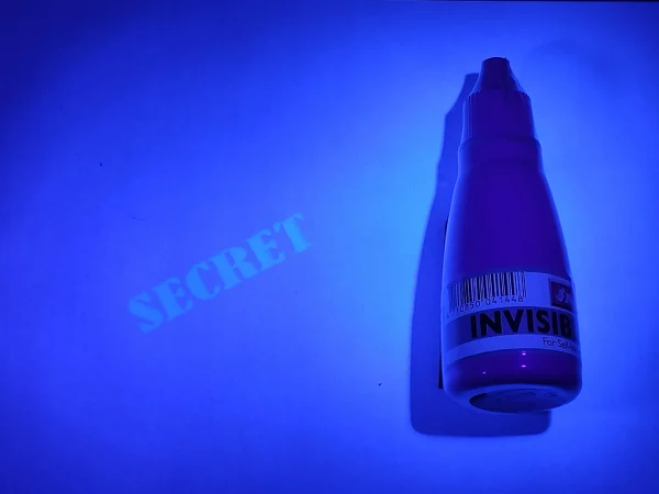 Imagen de tinta sellos fluorescente bajo luz ultravioleta, revelando un sello de fondo con la palabra 'secret'