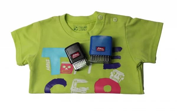 Kit Sello automático tejidos con camiseta marcada con dos sellos automáticos personalizados para tejidos encima.